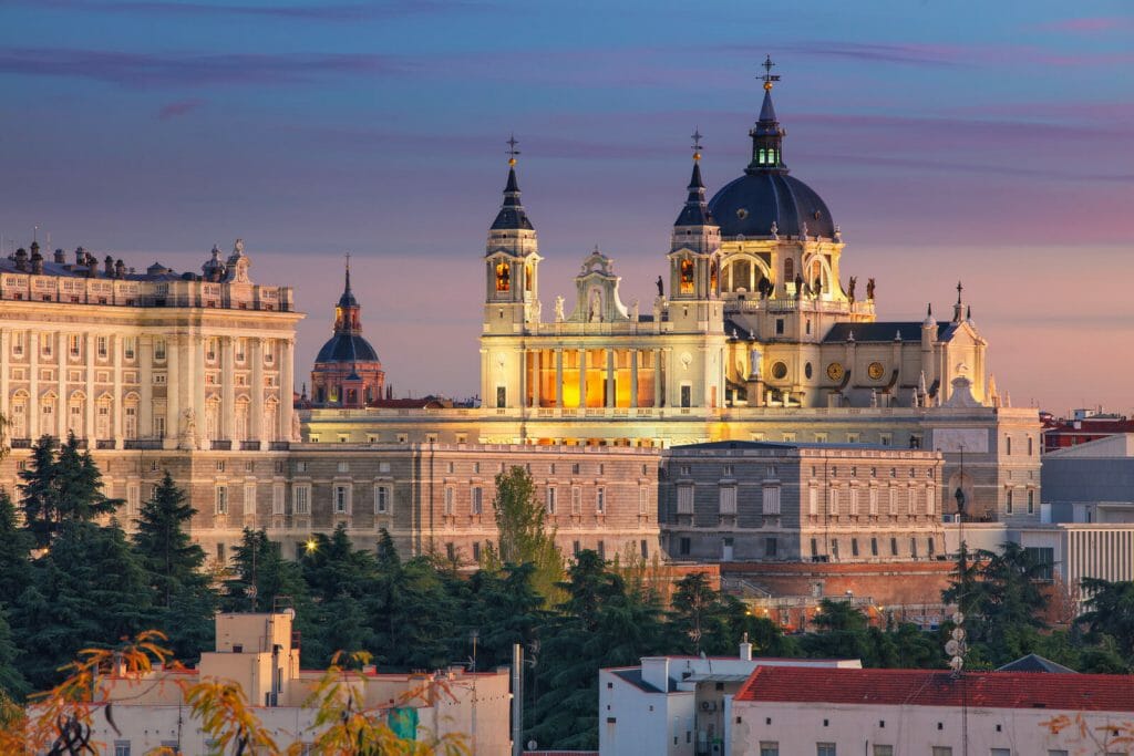 Image of Madrid skyline with Santa Maria la Real de La Almudena Cathedral and the Royal Palace during sunset.