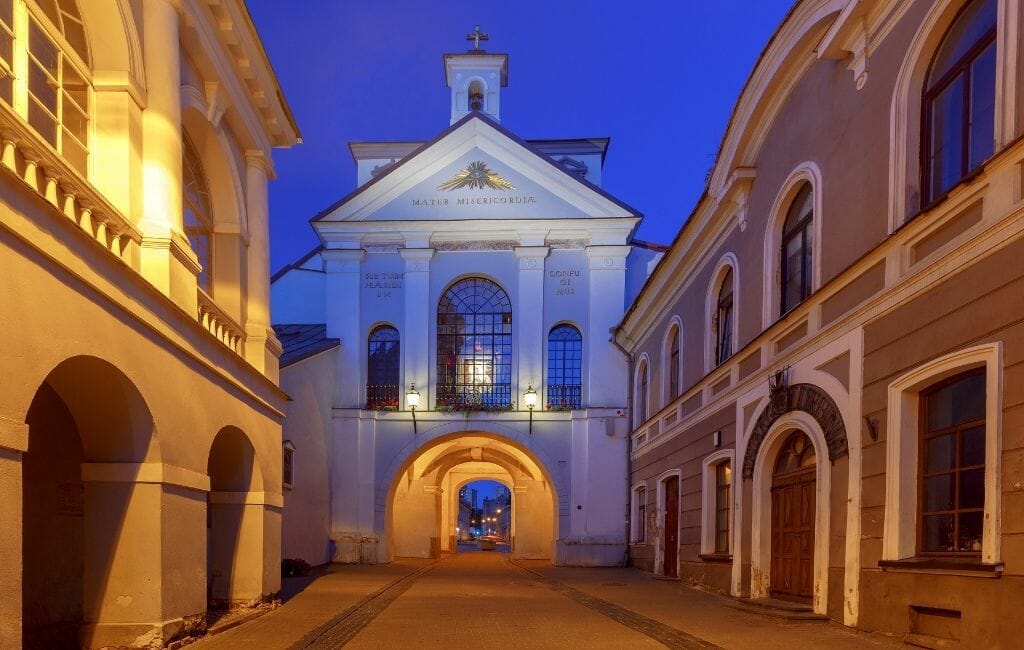 Street leading up to Old city gate of the city wall surrounding Vilnius photographed during blue hour. 