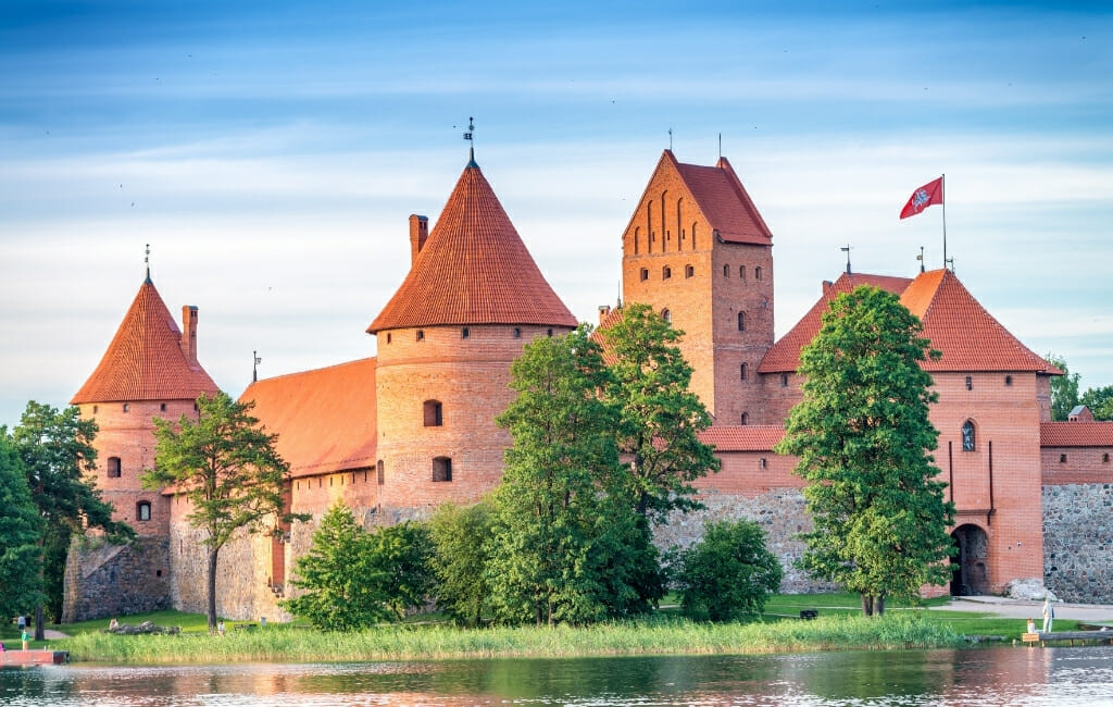 Orange colored castle with several towers surrounded by a lake