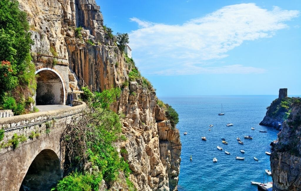 Narrow road and tunnel perched on a steep cliff along the ocean at the Amalfi Coast Italy