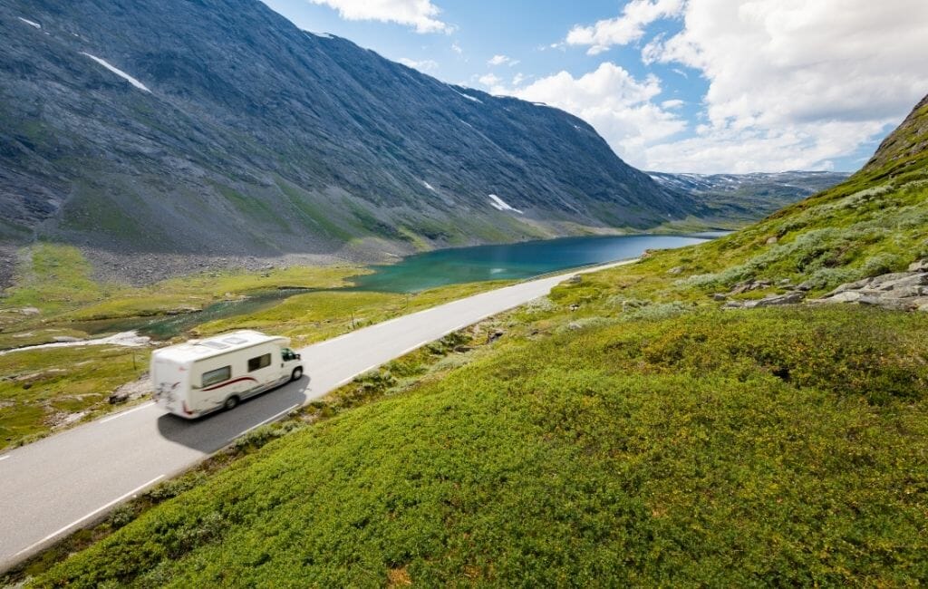 White Rv driving on a road in Norway through a Valley 