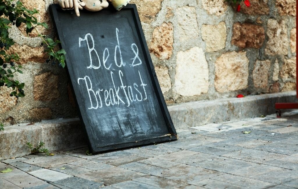 old stone wall with antique sign that reads:Bed and Breakfast in chalk