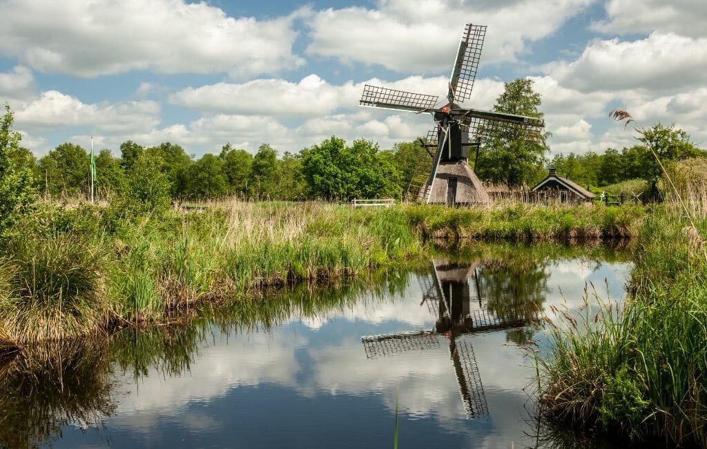 Small wooden windmill on a grass meadow next to canal near Giethoorn