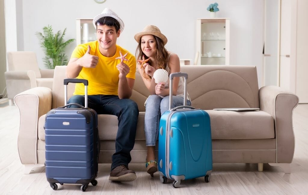 couple sitting on couch with suitcases in front of them