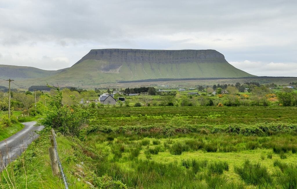 green pastures in the foreground and a "table-top" like mountain in the background, grey sky - Things to do in Sligo Ireland -  Knocknarae