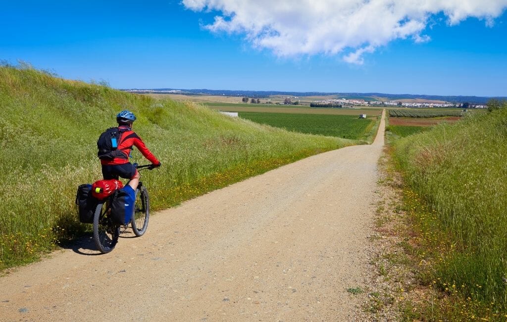 Biker on a gravel road in lush green hilly landscape