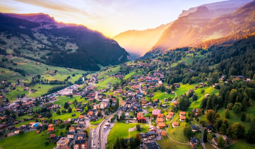 Aerial view over Grindelwald, a village in the valley in the swiss alps surrounded by mountains during sunset