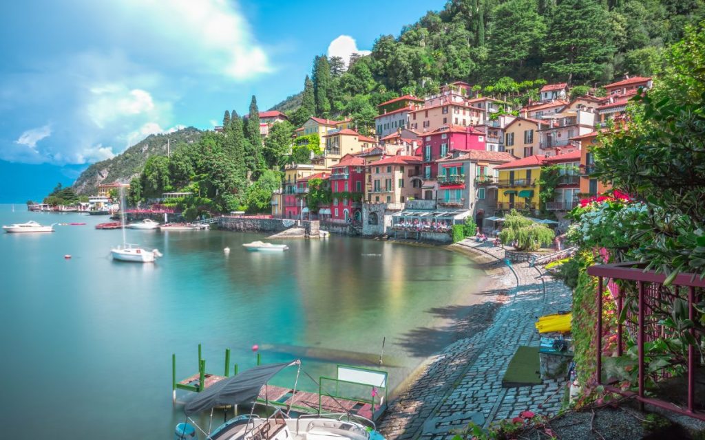 Shoreline of Varenna with white houses and red roofs built on the hilly shore of Lake Como