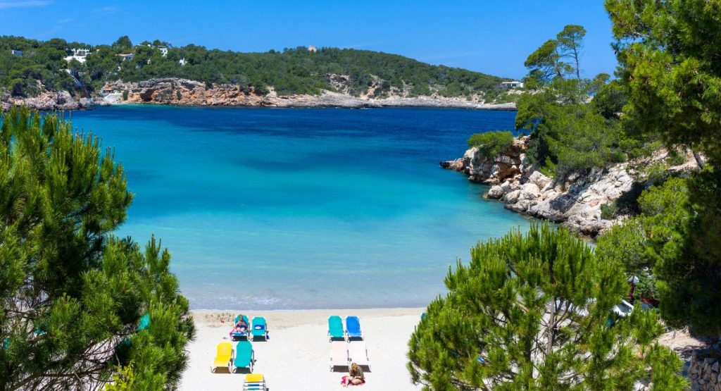 Small beach cove on bright blue water of Mediterranean Sea on sunny summer day. Yoga Ibiza.