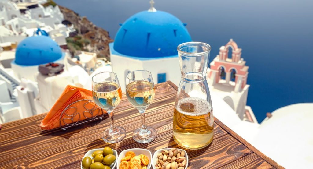 table with wine and small plates on table overlooking blue church domes in Santorini - best restaurants in Santorini