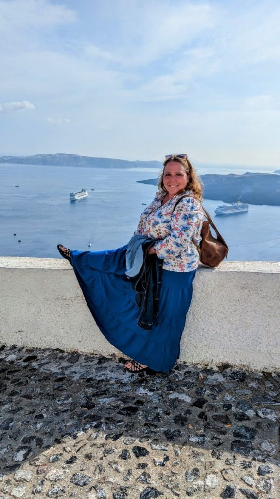 Maria Haase Travel Writer sitting on a wall overlooking the Caldera of Santorini