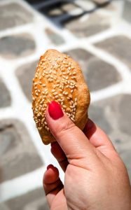 hand holding pastry with sesame seeds - Mykonos Food Tour