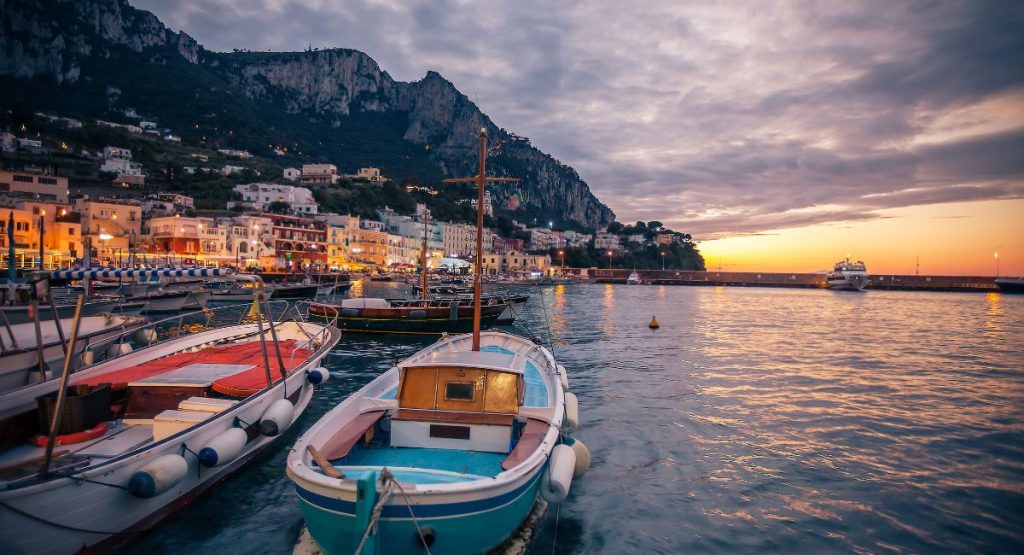 sunset view over Marina Grande in Capri with village in the background and fishing boats in the front