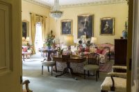 Living room with cushy furniture, chandelier, and large painted portraits on wall. Middlethorpe Hall & Spa, where to stay in York.
